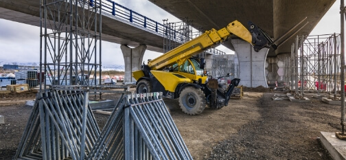 Boom forklift at construction site under a highway bridge