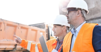 Two men in safety orange on a construction site